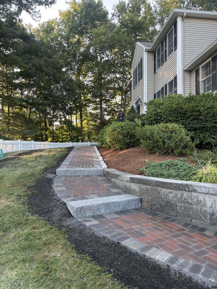 Brick paver walkway with granite steps climbing a landscaped slope