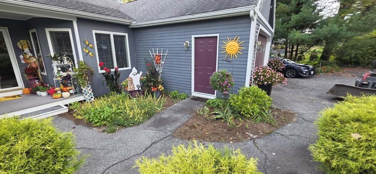Front foundation planting beds along a blue farmhouse
